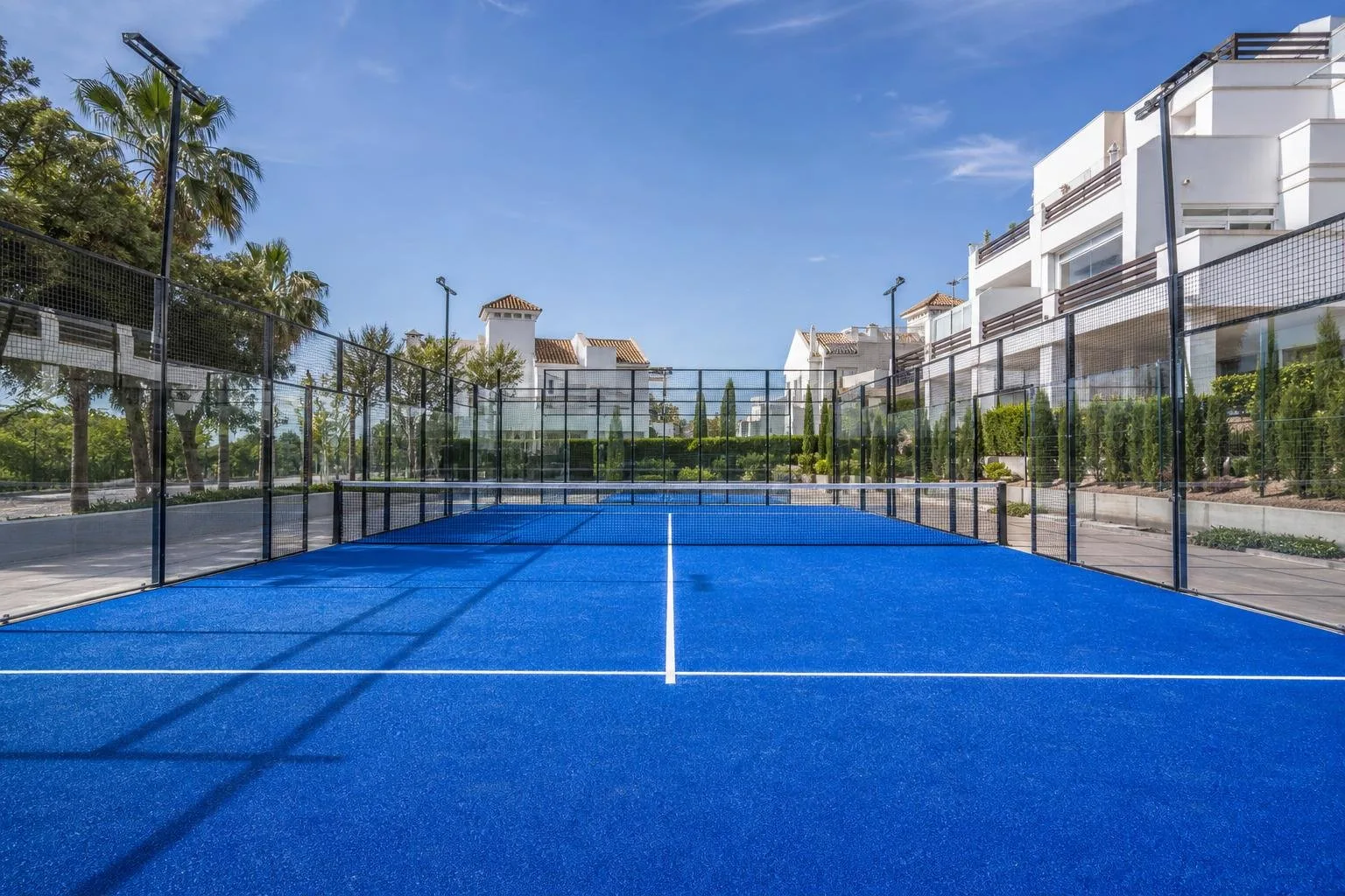 Pista de pádel con pavimento azul en una urbanización